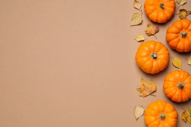 Fresh ripe pumpkins and autumn leaves on brown background, flat lay. Space for text