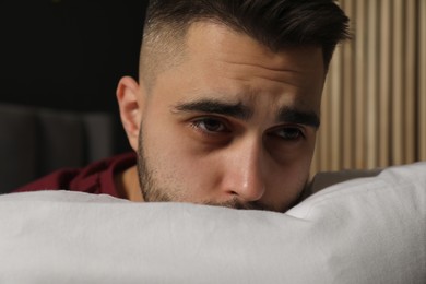 Photo of Sad young man with pillow at home