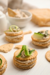 Delicious crackers with humus and cucumber on white wooden table