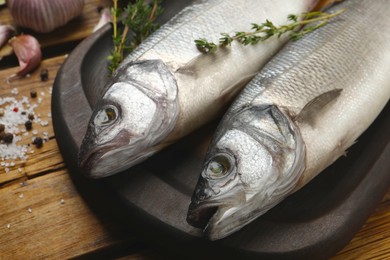 Sea bass fish and ingredients on wooden table, closeup