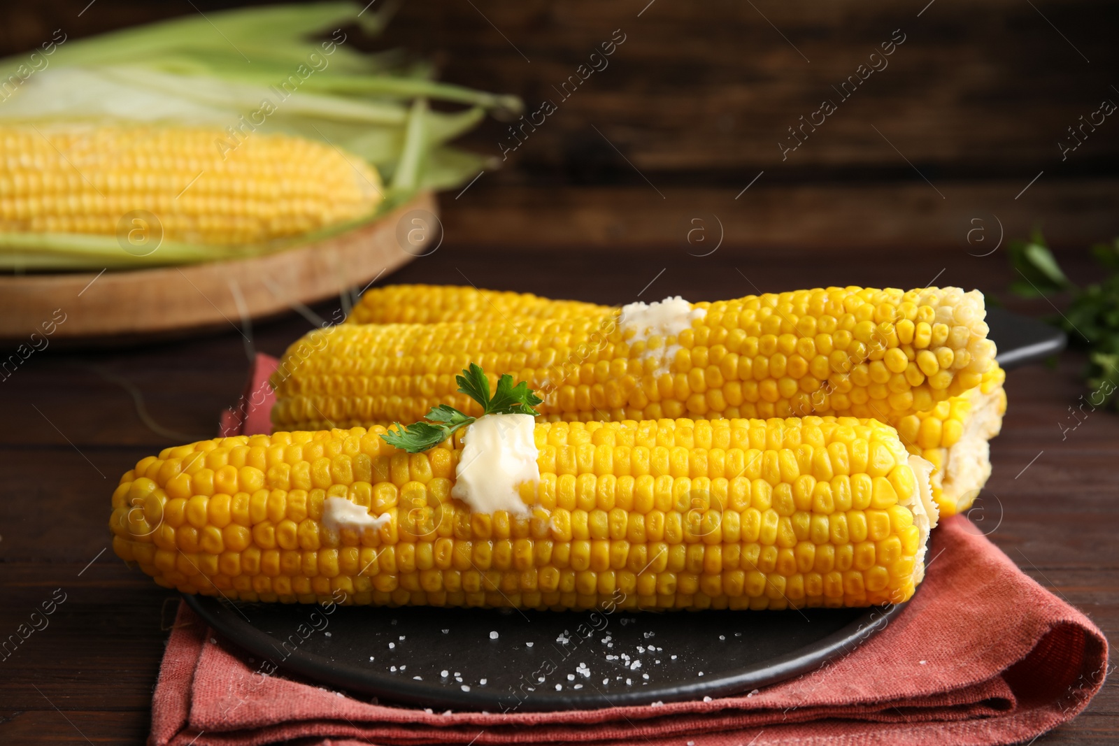 Photo of Fresh corn cobs with butter on table