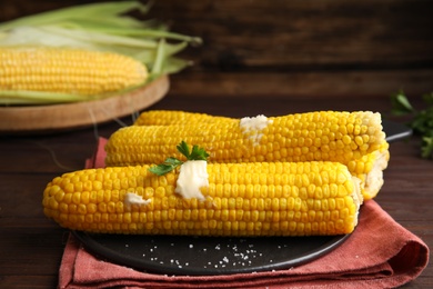 Photo of Fresh corn cobs with butter on table