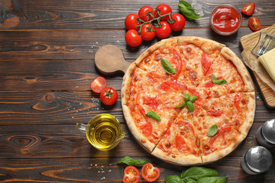 Delicious pizza Margherita and ingredients on wooden table, flat lay