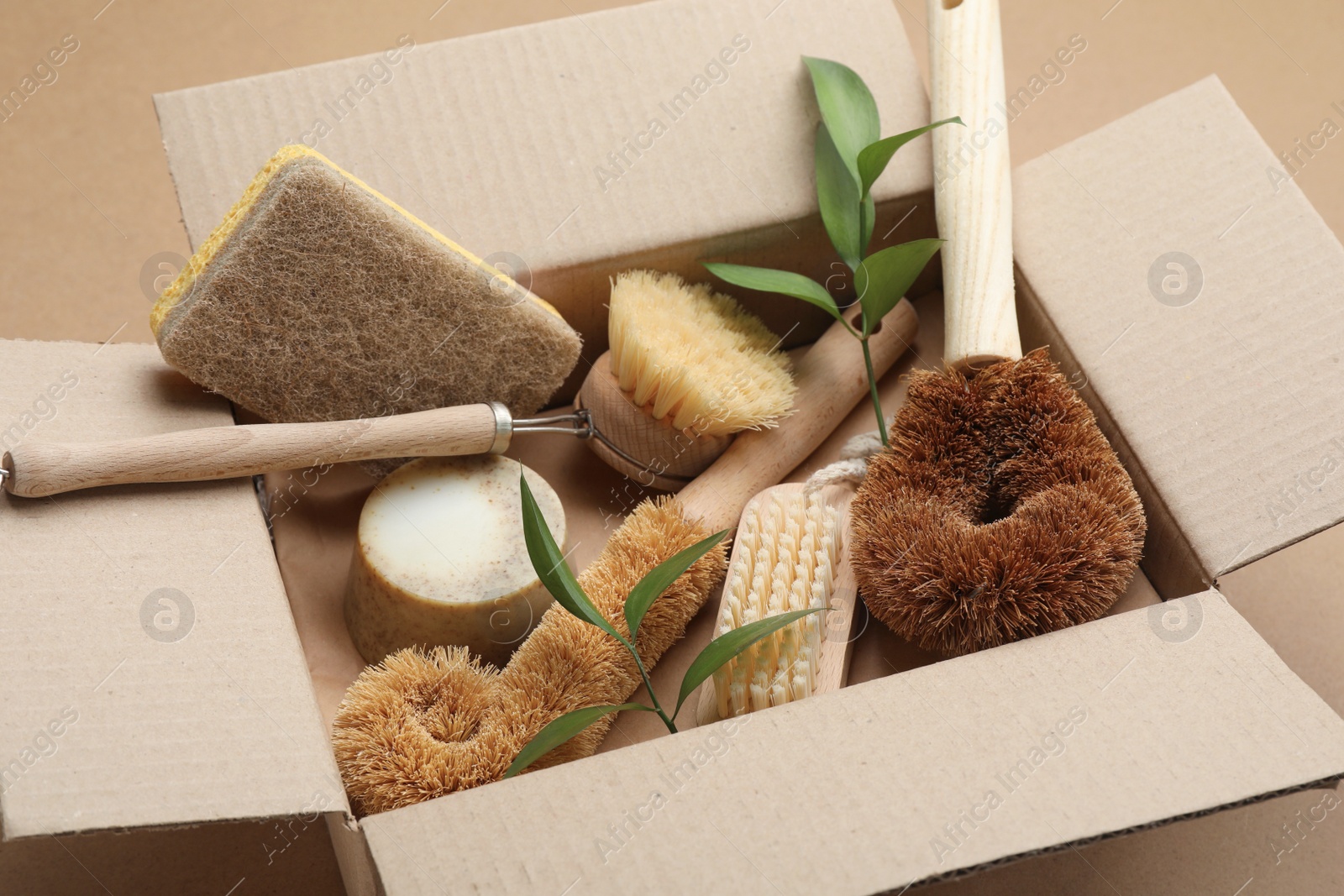 Photo of Cardboard box with eco friendly products on craft paper, closeup
