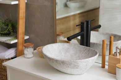 Stone vessel sink with faucet and toiletries on white countertop in bathroom