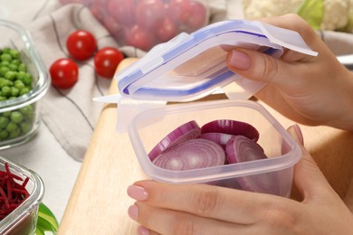 Photo of Woman closing plastic container with lid at table, closeup. Food storage