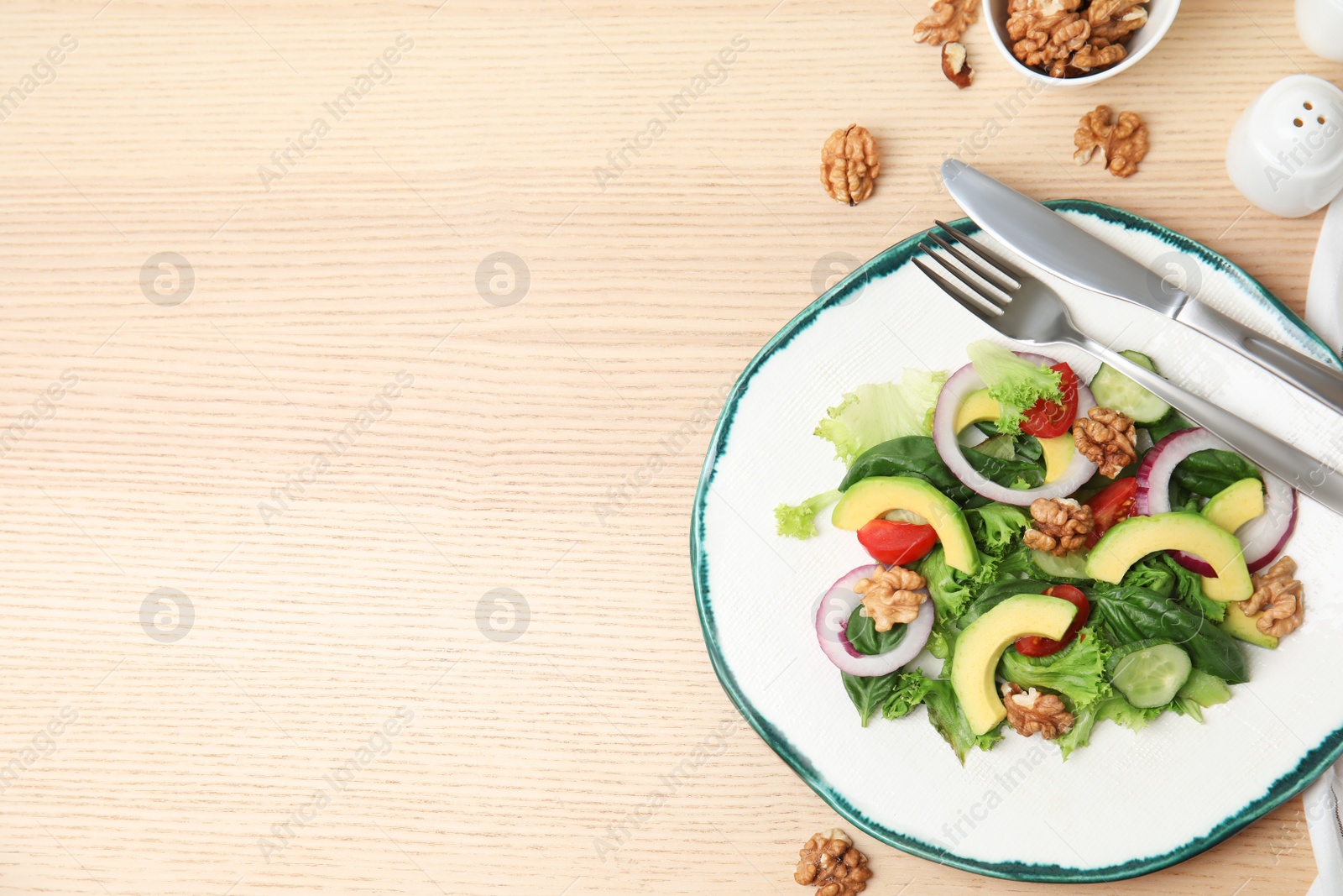 Photo of Delicious avocado salad with walnuts on wooden table, flat lay. Space for text