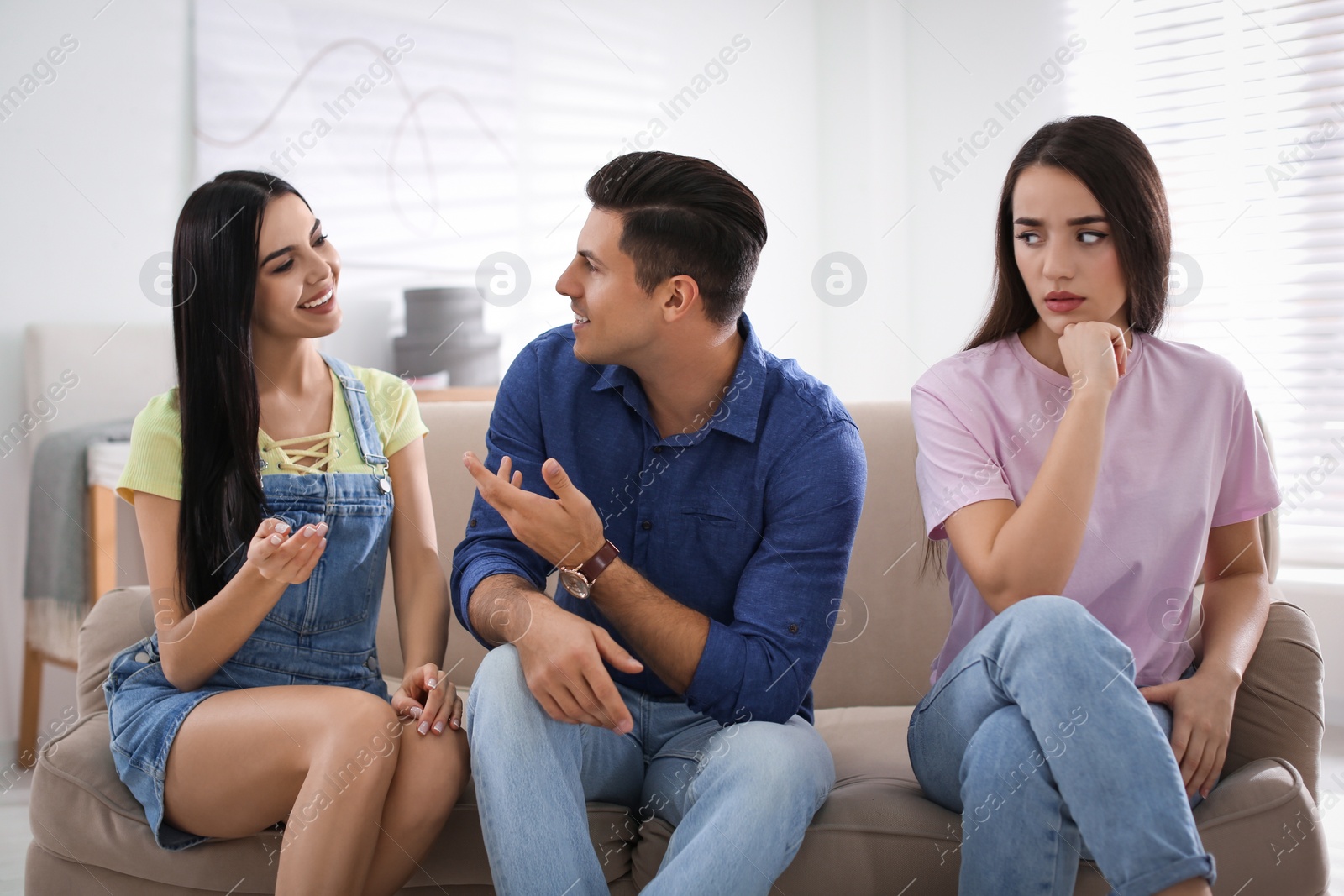 Photo of Unhappy woman feeling jealous while couple spending time together at home