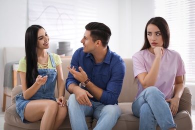 Unhappy woman feeling jealous while couple spending time together at home