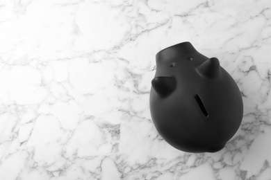Black piggy bank on marble table, top view