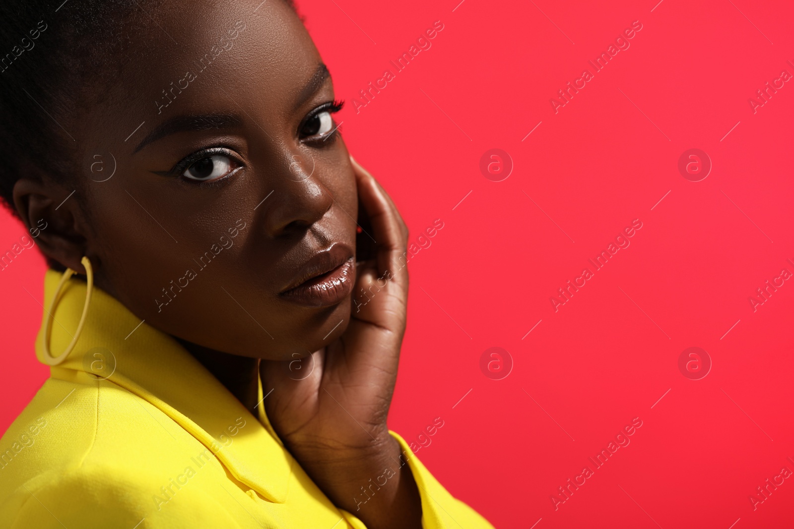 Photo of Fashionable portrait of beautiful woman on coral background, closeup. Space for text