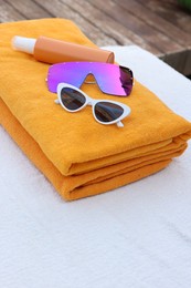 Photo of Beach towels, sunglasses and sunscreen on sunbed at resort