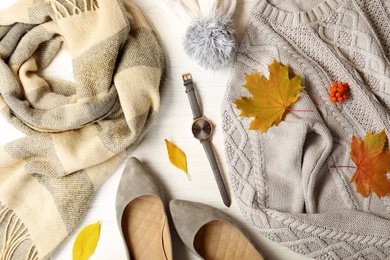 Photo of Stylish outfit and autumn leaves on white wooden background, flat lay. Trendy warm clothes