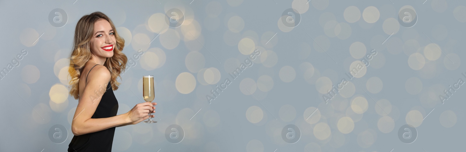 Image of Beautiful woman holding glass of champagne on grey background, space for text. Christmas party, banner design