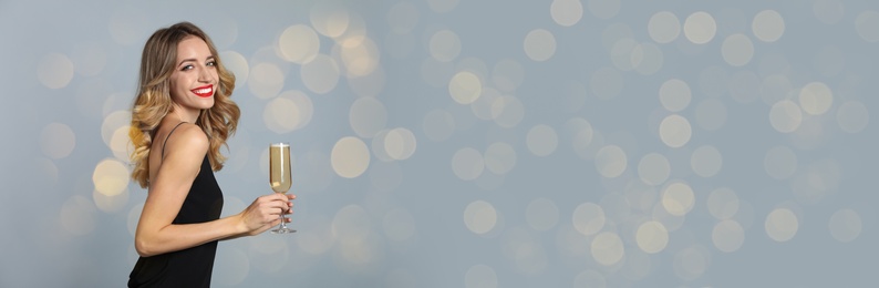 Image of Beautiful woman holding glass of champagne on grey background, space for text. Christmas party, banner design