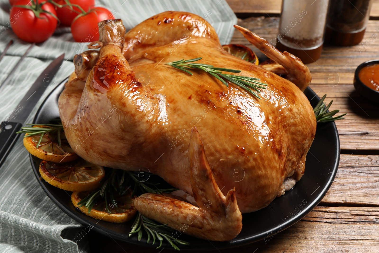 Photo of Tasty roasted chicken with rosemary and lemon on wooden table