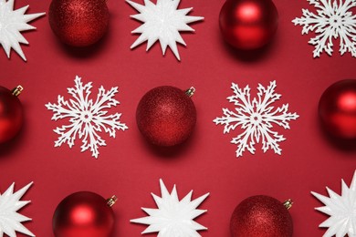 Photo of Christmas balls and decorative snowflakes on red background, flat lay
