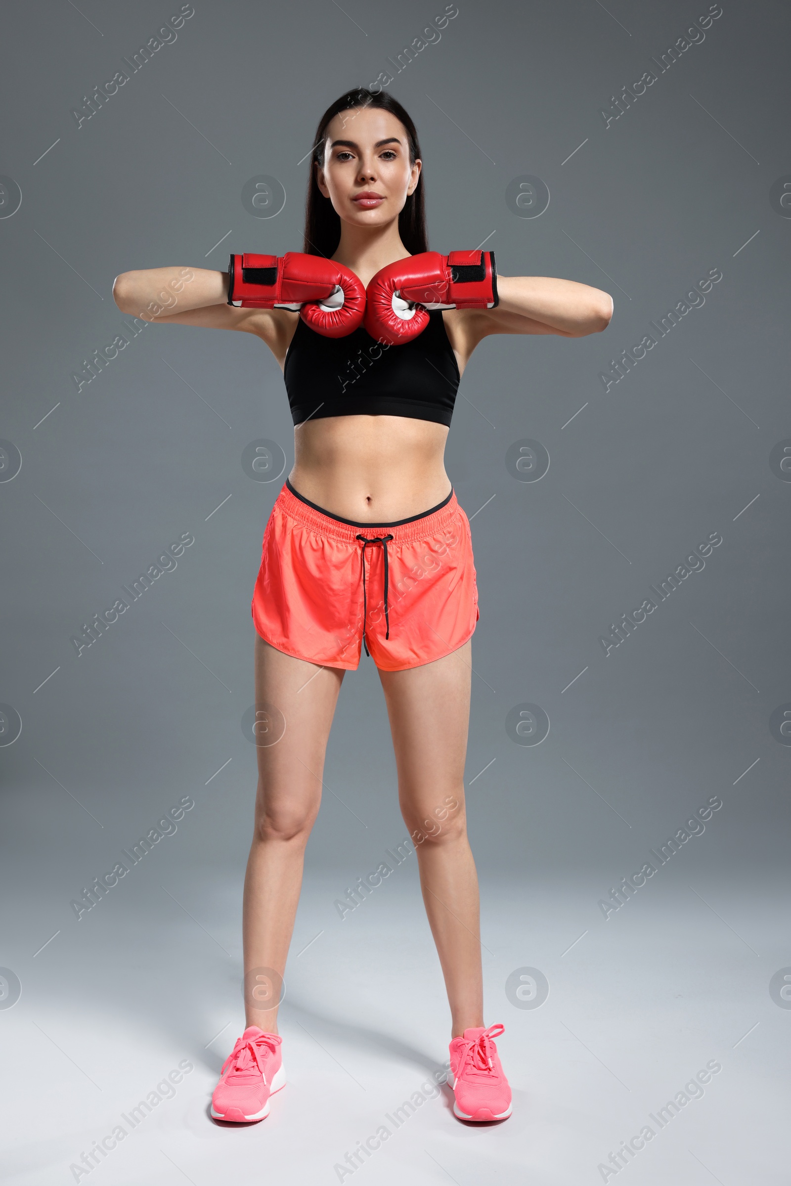 Photo of Beautiful woman in boxing gloves on grey background