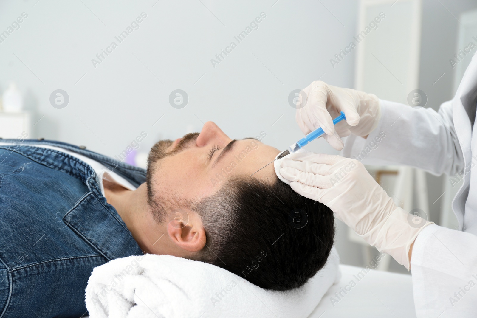 Photo of Man with hair loss problem receiving injection in salon