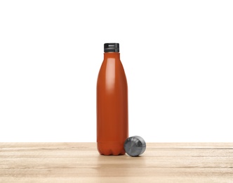 Stylish thermo bottle on wooden table against white background