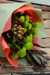 Photo of Bouquet of beautiful flowers wrapped in paper on wooden table, top view