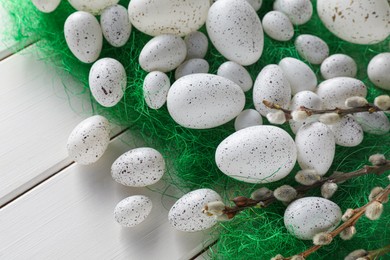 Many beautifully painted Easter eggs and pussy willow branches on white wooden table