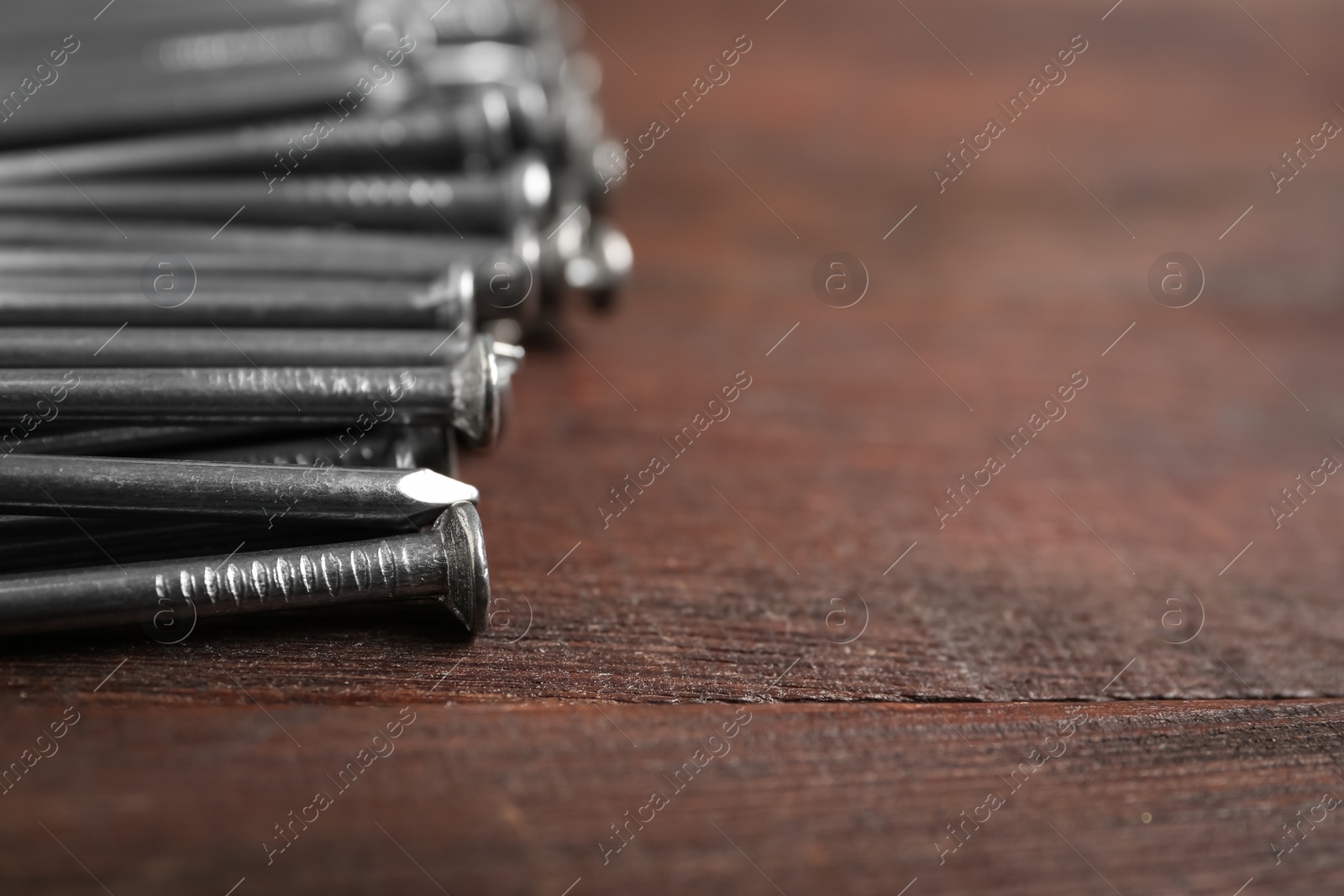 Photo of Many metal nails on wooden background, closeup. Space for text