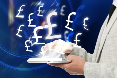 Money exchange concept. Businessman with tablet computer on blue background, closeup. Pound currency symbols over device