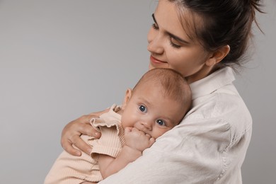 Photo of Beautiful mother with her cute baby on grey background. Space for text