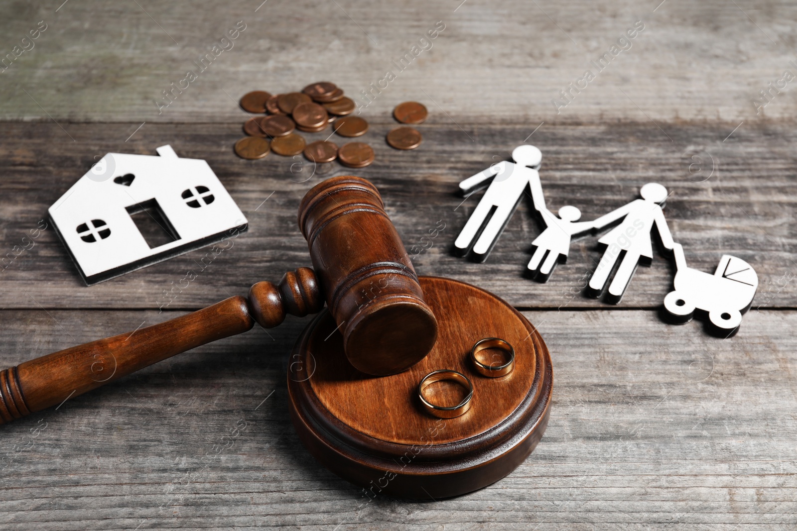 Photo of Divorce concept. Gavel, wedding rings and paper cutout of family on wooden table