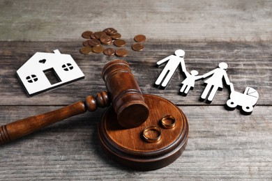 Divorce concept. Gavel, wedding rings and paper cutout of family on wooden table