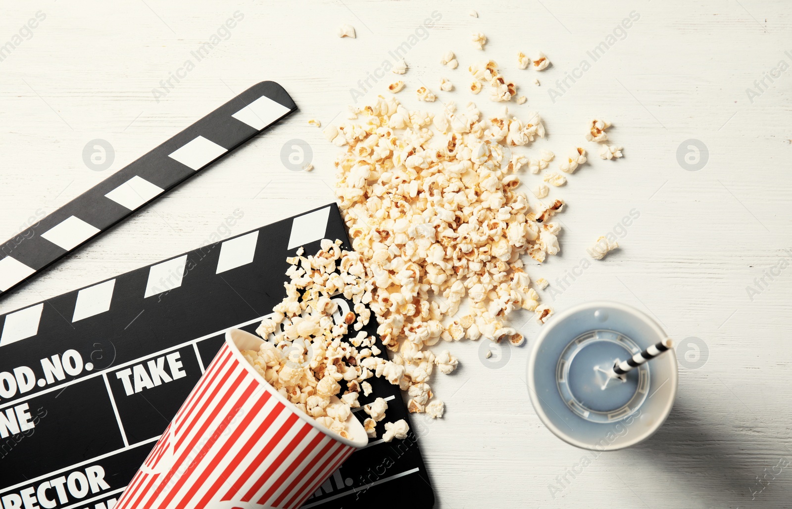 Photo of Tasty popcorn, drink and clapperboard on wooden background, top view. Cinema snack