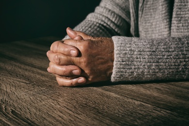 Poor senior woman at table, closeup of hands