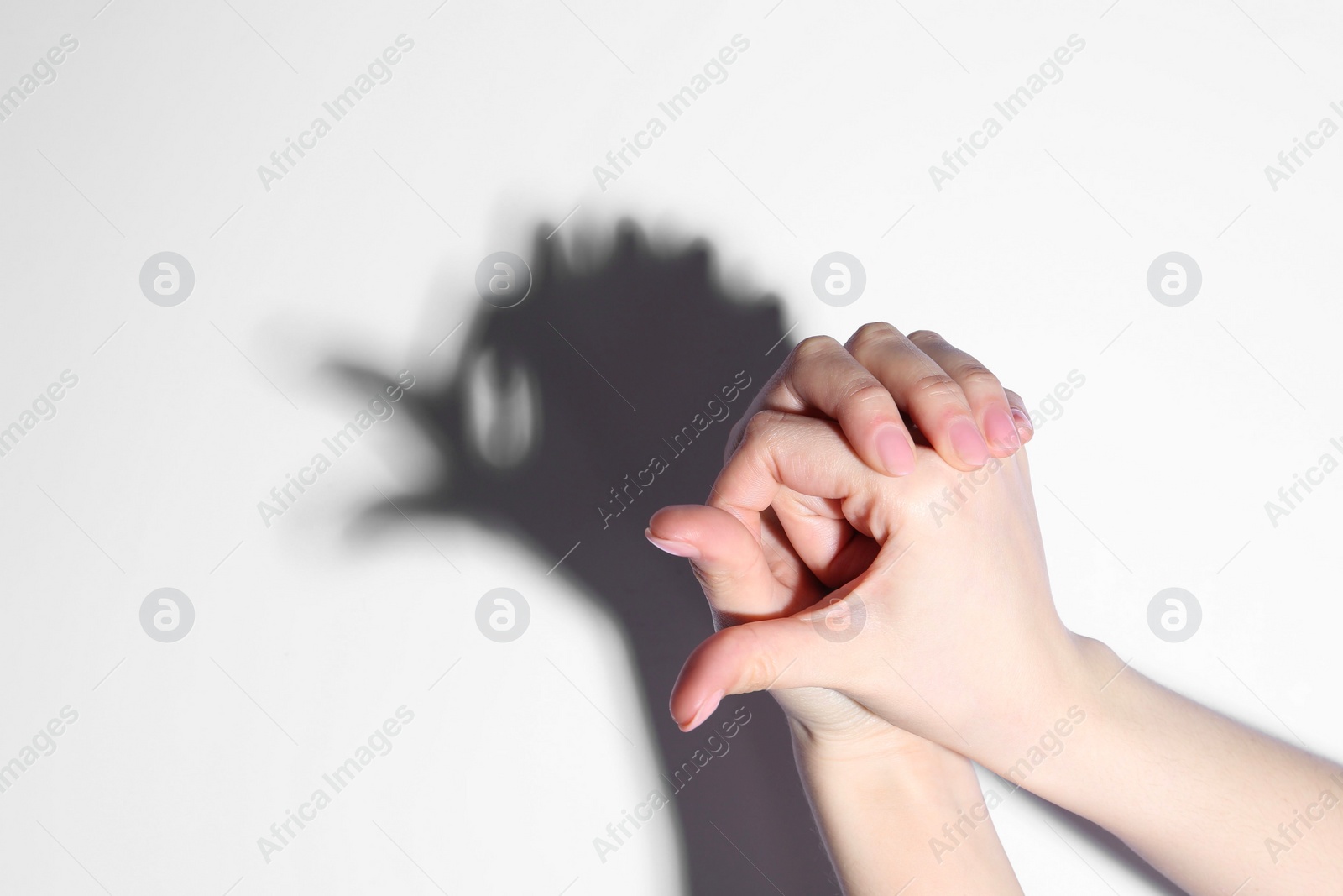 Photo of Shadow puppet. Woman making hand gesture like bird on light background, closeup