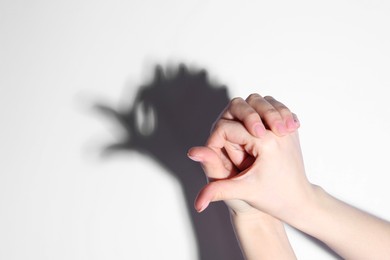 Shadow puppet. Woman making hand gesture like bird on light background, closeup