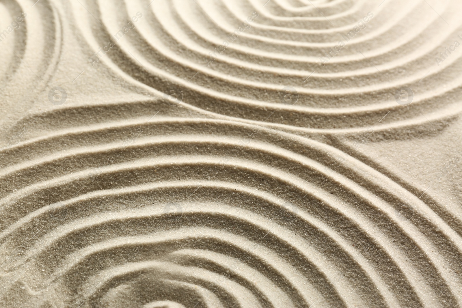 Photo of Beautiful patterns on sand, closeup. Zen garden