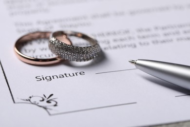 Photo of Marriage contract, pen and wedding rings, closeup