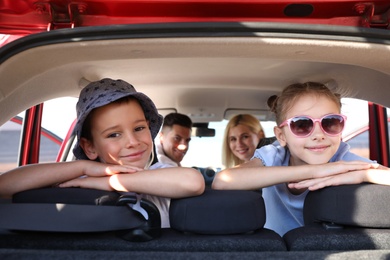 Photo of Happy family in car on sunny summer day, view through open trunk
