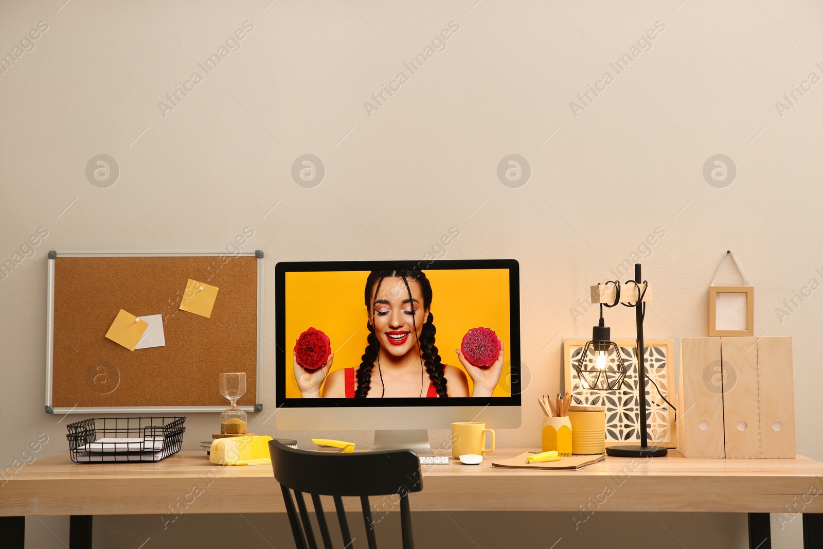 Photo of Stylish workplace with computer on wooden desk near light wall. Interior design