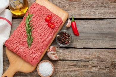 Photo of Raw fresh minced meat and ingredients on wooden table, flat lay. Space for text