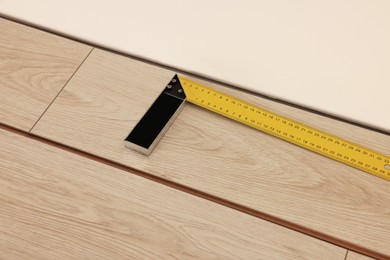 Photo of Ruler and parquet planks on floor in room
