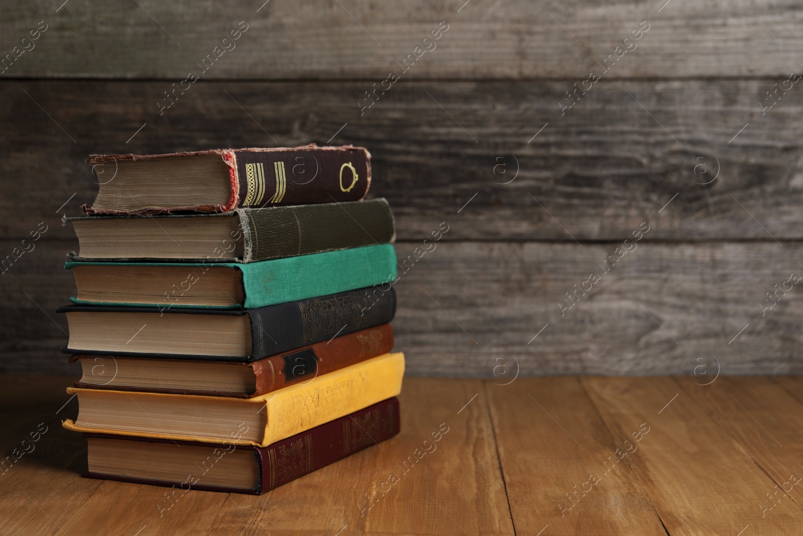 Photo of Stack of old hardcover books on wooden table, space for text