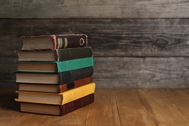 Photo of Stack of old hardcover books on wooden table, space for text