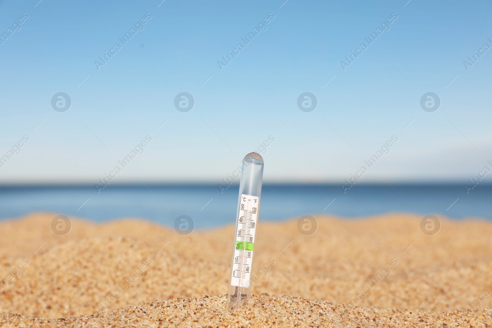 Photo of Weather thermometer in sand near sea, space for text