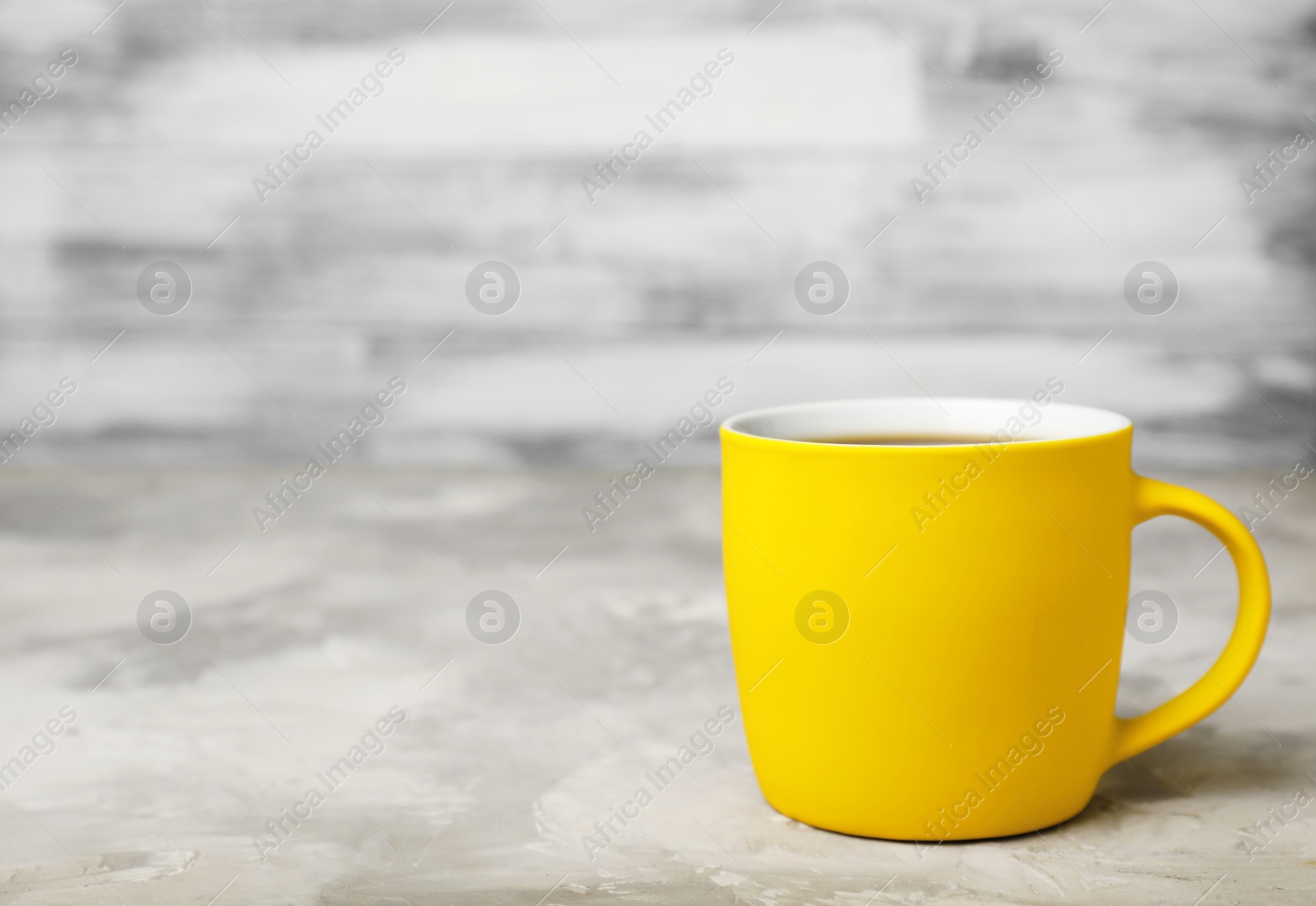 Photo of Yellow ceramic cup with hot aromatic coffee on table