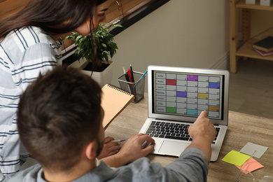 Colleagues working with calendar app on laptop in office