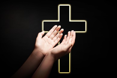 Image of Christian cross and woman stretching hands towards light in darkness, closeup