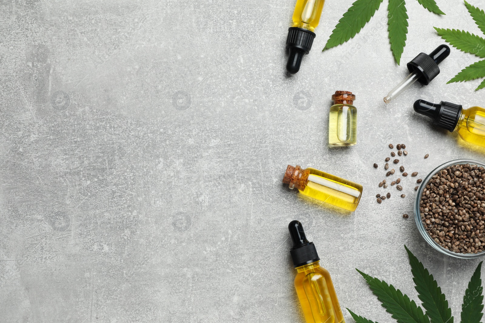 Photo of Hemp oil, seeds and leaves on light grey table, flat lay. Space for text