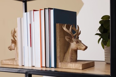 Photo of Wooden deer shaped bookends with books on shelf indoors