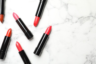 Photo of Different lipsticks and space for text on marble background, flat lay